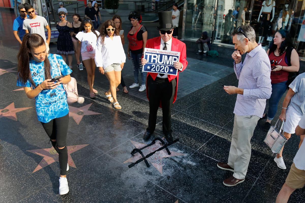 Apoiador de Trump posa diante da estrela do presidente americano, que foi vandalizada na Calçada da Fama, em Hollywood | Katharine Lotze/Getty Images/AFP