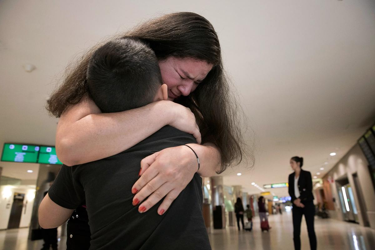 Mãe reencontra filho, no aeroporto de Baltimore-Washington, do qual foi separada ao entrarem nos Estados Unidos | WIN MCNAMEE/AFP
