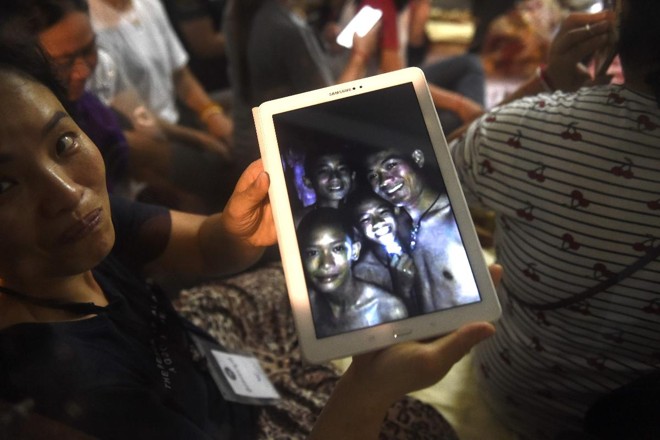 Pais mostram foto de quatro dos 12 meninos que estão presos em uma caverna no Norte da Tailândia | LILLIAN SUWANRUMPHA/AFP