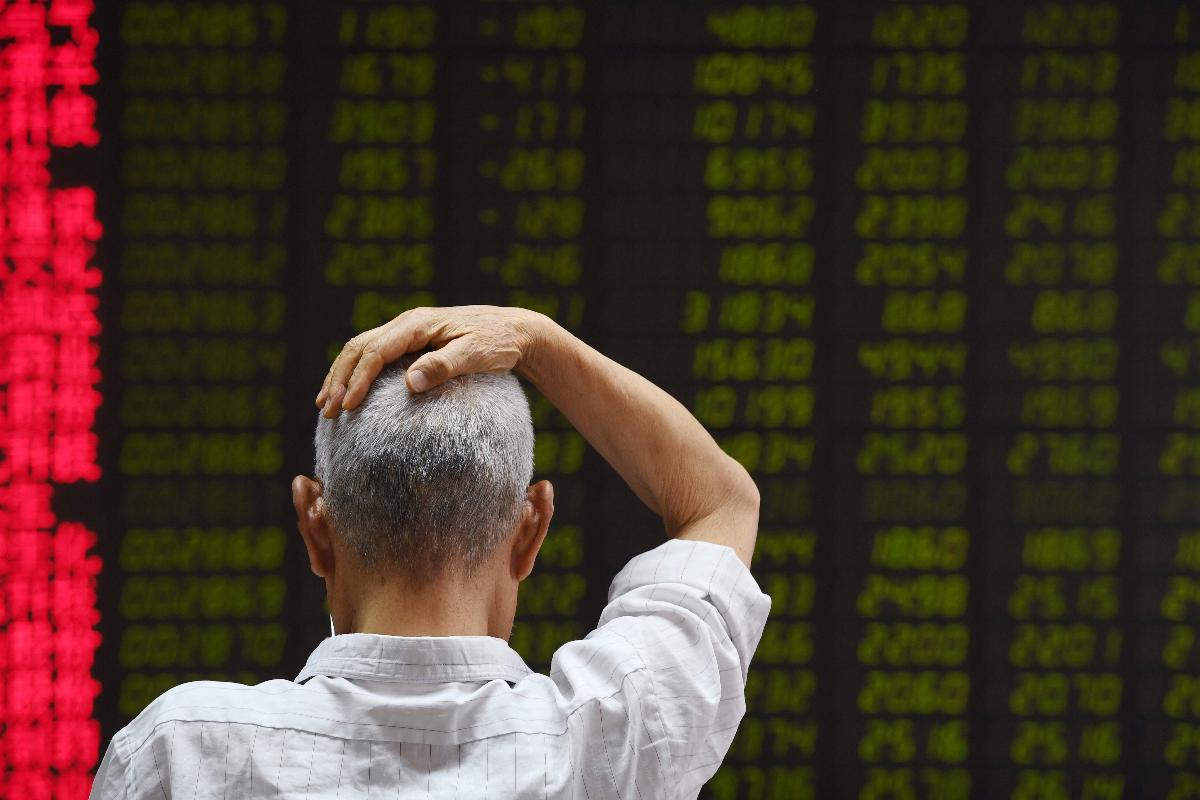 Um homem verifica a flutuação dos preços na bolsa de valores de Pequim, enquanto aumentam as tensões de uma guerra comercial mundial | GREG BAKERAFP