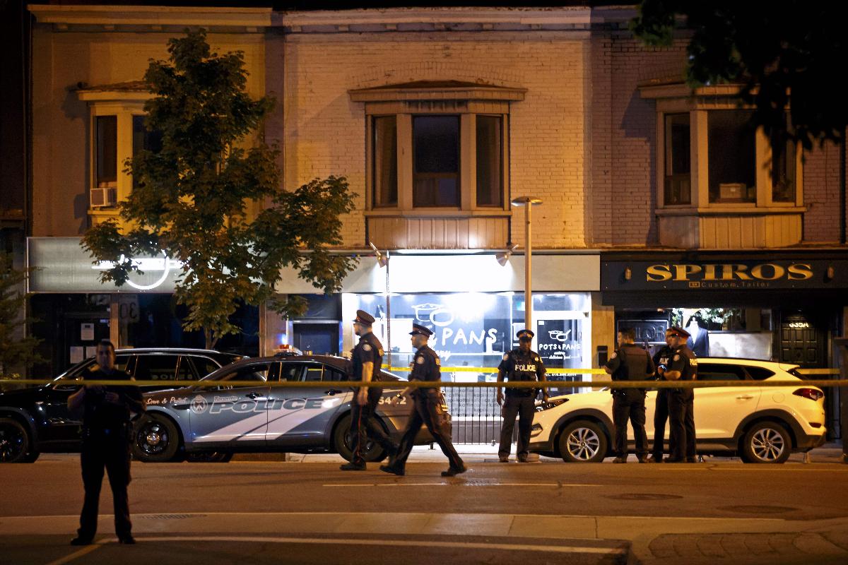 Policiais em frente ao local onde ocorreu o tiroteio, na Avenida Danfoth, centro de Toronto, Canadá | COLE BURSTONAFP