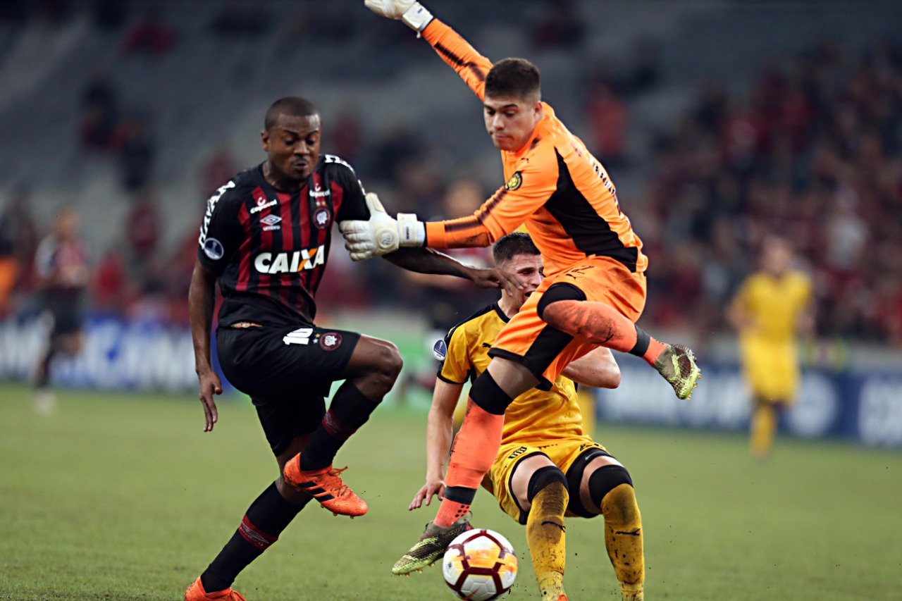 Marcelo Cirino ganha a dividida com o goleiro e o zagueiro do Peñarol, que bateram cabeça no segundo gol do Furacão. | Albari Rosa/Gazeta do Povo