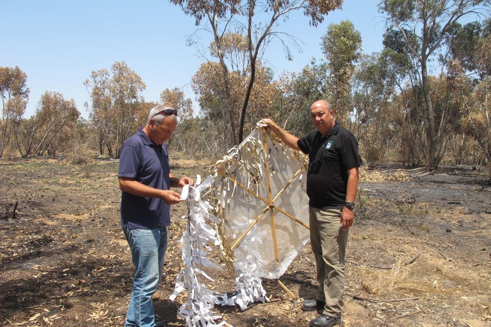 Pipas incendiárias desafiam o exército de Israel, um dos mais poderosos do mundo David ben David (E) e Erez Shtein seguram uma pipa incendiária que caiu em um terreno próximo à fronteira entre Israel e a Faixa de Gaza | Ruth Eglash/Washington Post