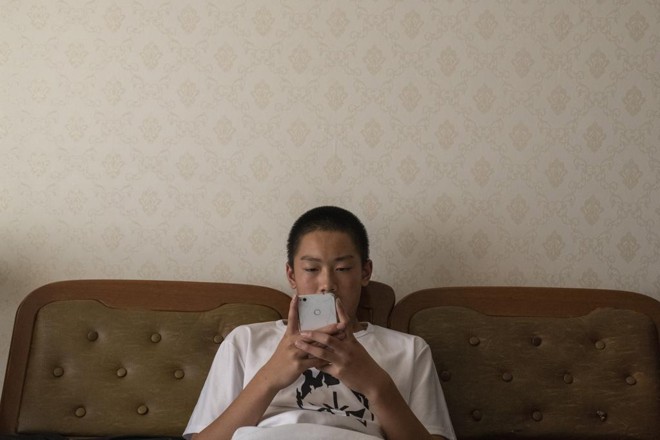 Jovem chinês mexe em seu celular, que não tem acesso aos meus apps a que os brasileiros estão acostumados. | Gilles Sabriê/NYT