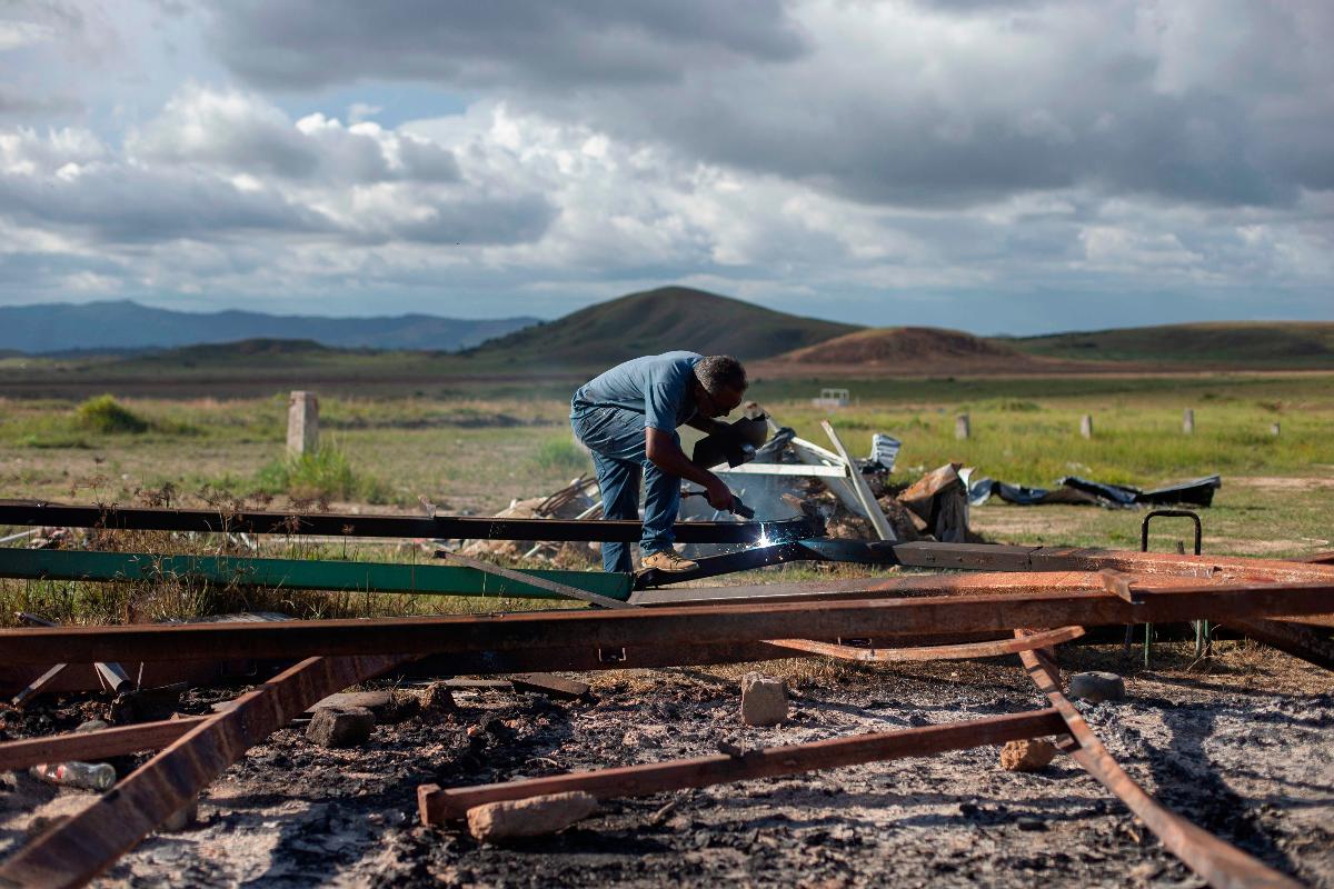 Homem corta a estrutura metálica de um abrigo usado por refugiados venezuelanos que foi destruído por brasileiros, na cidade fronteiriça de Pacaraima, Roraima. Moradores de Pacaraima expulsaram imigrantes venezuelanos de seus acampamentos improvisados, em meio a crescentes tensões regionais. Dezenas de milhares de venezuelanos cruzaram a fronteira para o Brasil nos últimos três anos ao tentar escapar da crise econômica, política e social que assola seu país. | MAURO PIMENTEL/AFP