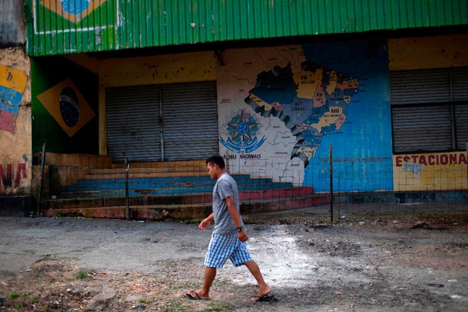 Um homem passa em frente ao que era um local improvisado para abrigar refugiados antes de ser queimado por moradores de Pacaraima no sábado | MAURO PIMENTEL/AFP