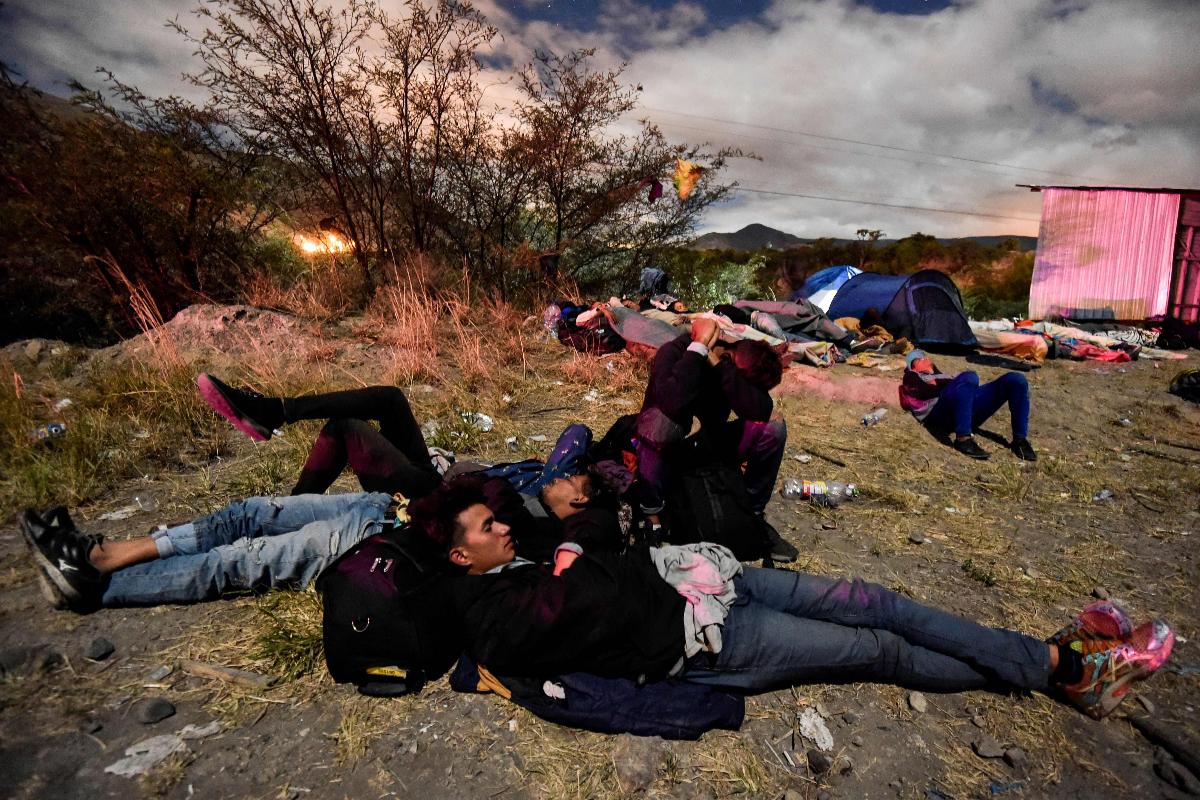 Migrantes venezuelanos que pretendem buscar refugio no Peru, descansam à margem de rodovia no Equador | LUIS ROBAYO/AFP