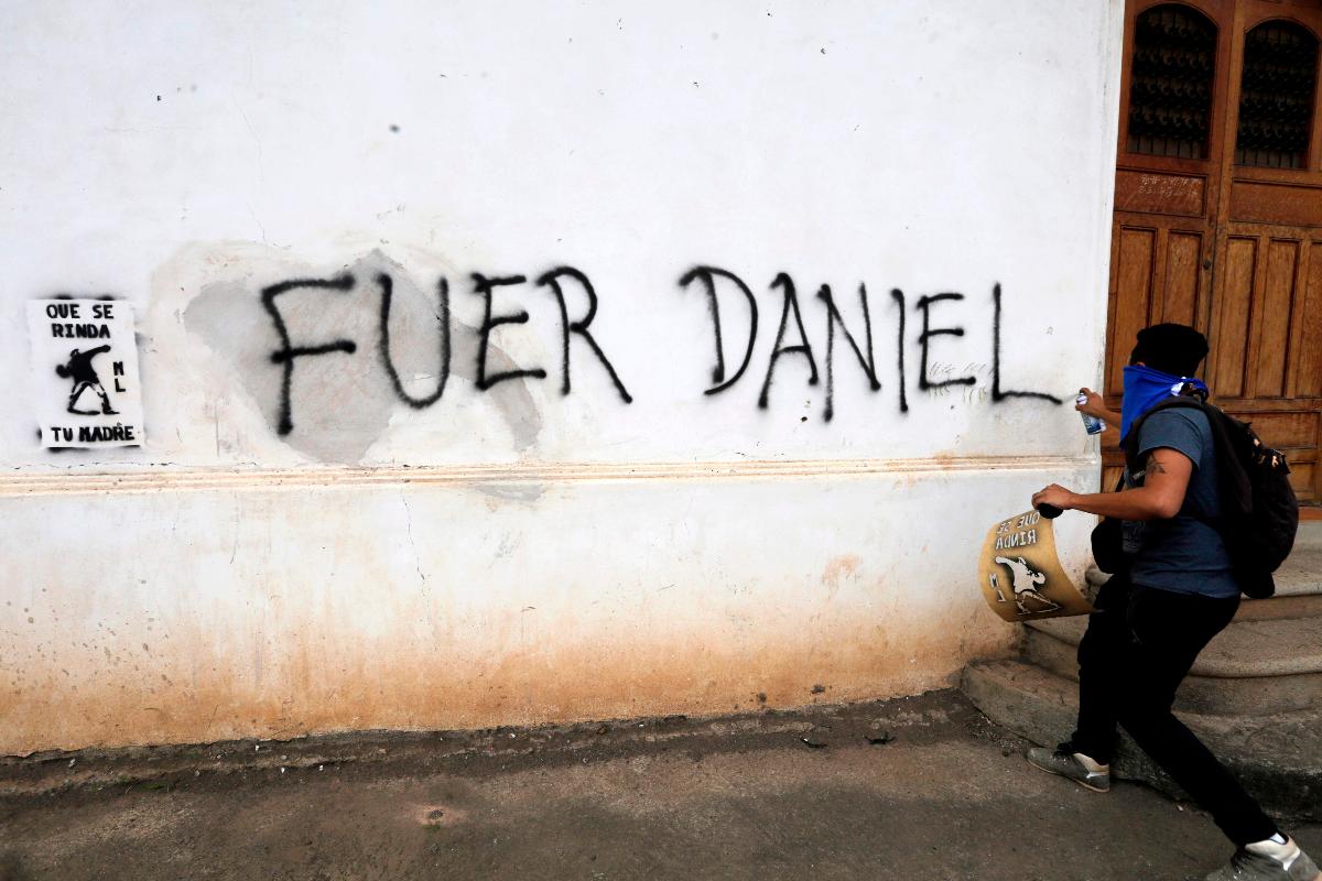 Um manifestante contra o governo faz um graffiti dizendo "Fora Daniel", referindo-se ao ditador da Nicarágua, Daniel Ortega, durante uma marcha em Granada, em 25 de agosto de 2018 | INTI OCON/AFP