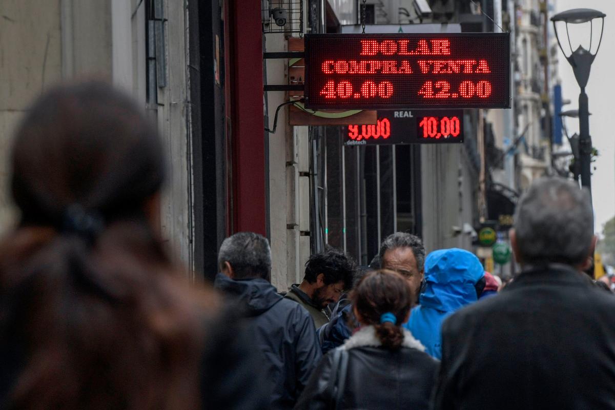 Argentinos passam por casa de câmbio em Buenos Aires | JUAN MABROMATA/AFP