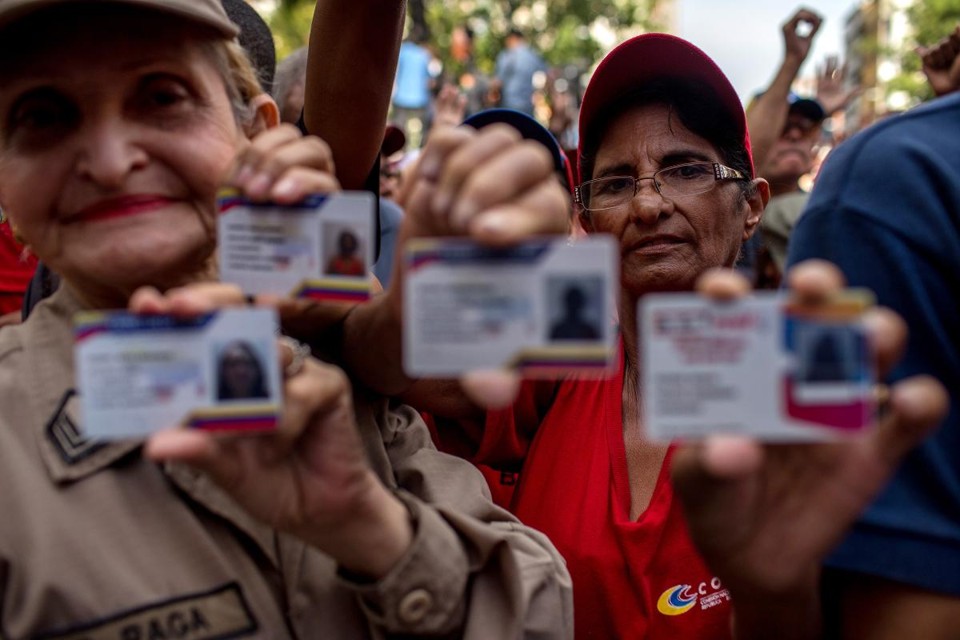 Venezuelanos mostram os Cartões da Pátria, em Caracas | Manaure Quintero/Bloomberg