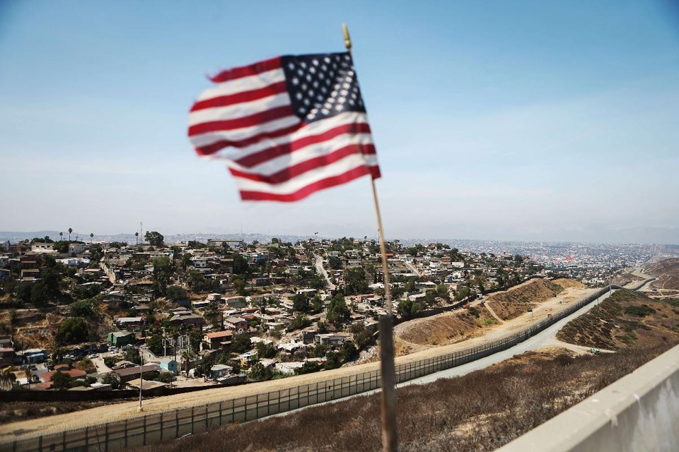 Vento agita bandeira americana na fronteira entre os EUA e o México | MARIO TAMA/AFP