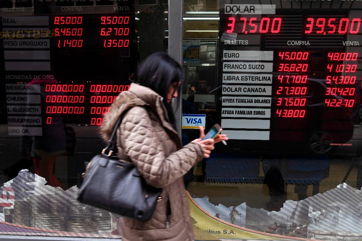 Mulher passa na frente de casa de câmbio em Buenos Aires: moeda argentina perdeu mais da metade do valor nos últimos 12 meses | EITAN ABRAMOVICH/AFP