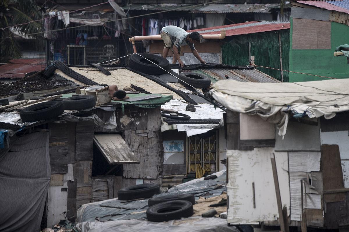 Morador de favela em Manila, capital das Filipinas, reforça teto de casa para evitar prejuízos com o tufão Mangkhut | NOEL CELIS/AFP