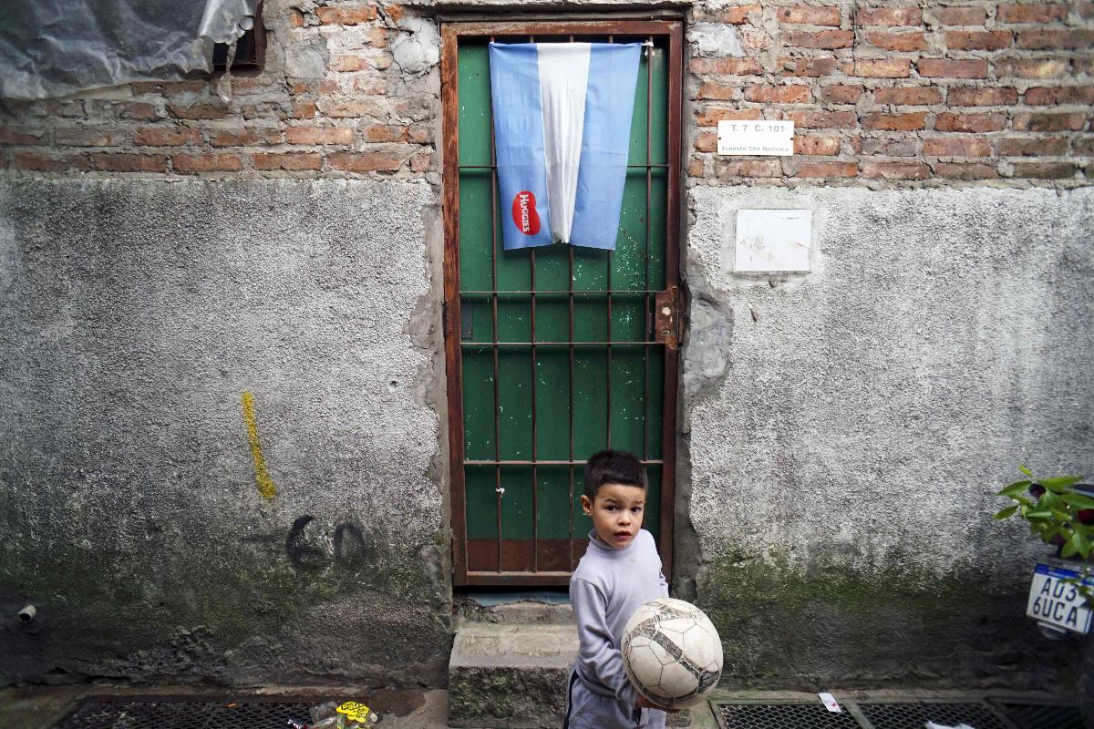 Um garoto joga bola em um beco da favela Villa Zavaleta em Buenos Aires, Argentina | EITAN ABRAMOVICH/AFP