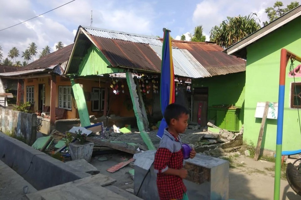 Criança passa por casa atingida por fortes tremores em Donggala, no Norte da Indonésia | BNPB/AFP
