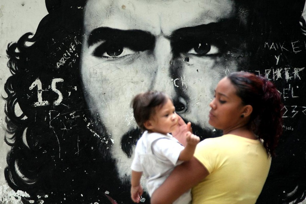 Uma mãe com seu filho passa por um grafitti retratando o revolucionário argentino Ernesto Che Guevara em um bairro de baixa renda de Caracas, em 8 de outubro de 2008.