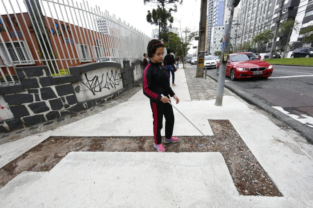 A estudante Maria Eduarda diz que fica perdida com a ausência do piso tátil que deveria orientá-la em frente ao IPC. | Aniele Nascimento/Gazeta do Povo