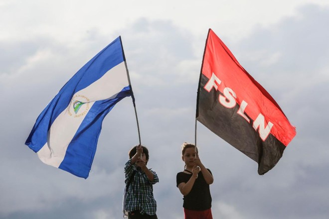Crianças agitam bandeiras da Nicarágua e do movimento sandinista, durante manifestação de apoio ao ditador Daniel Ortega | INTI OCON/AFP
