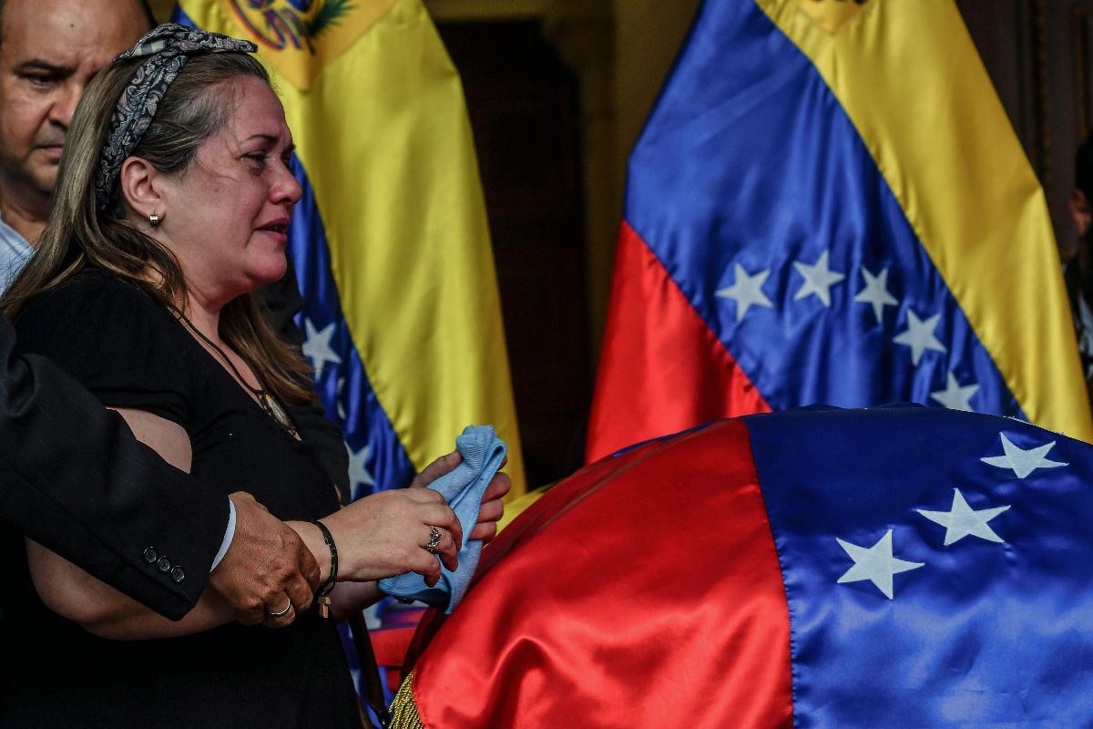 Irmã do vereador Fernando Alban chora diante do caixão dele, durante funeral na Assembleia Nacional | JUAN BARRETO/AFP
