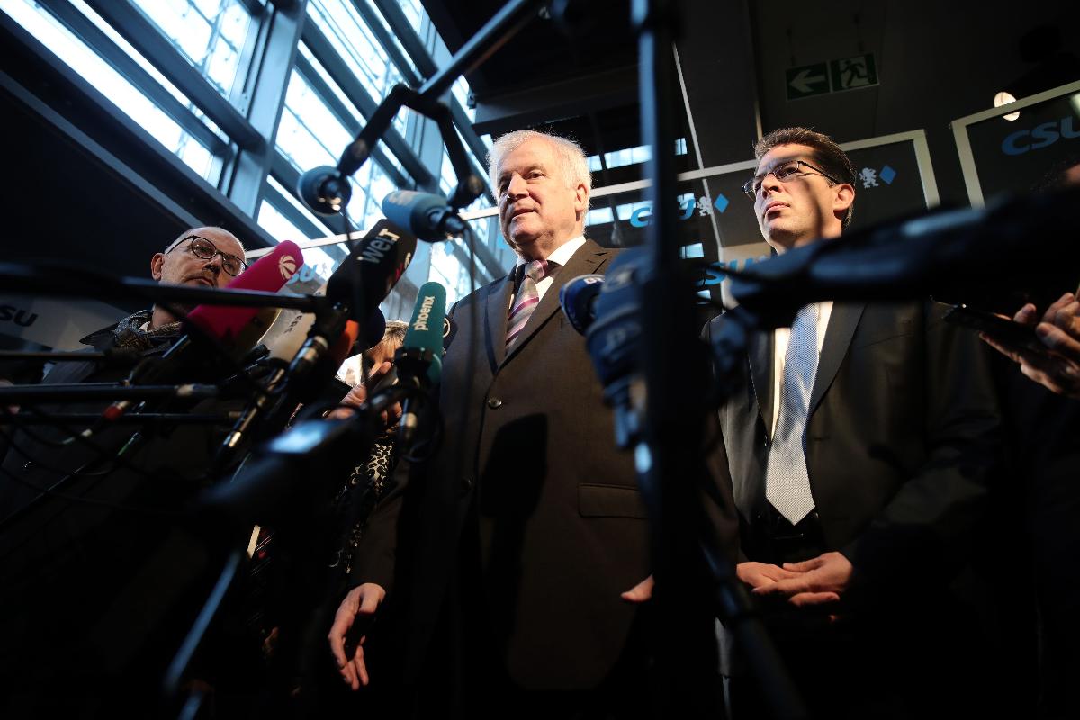 Ministro do Interior alemão e líder do conservador Partido Social-Cristão (CSU), Horst Seehofer (ao centro) fala com a imprensa após as eleições estaduais na Baviera | MICHAEL KAPPELER/AFP