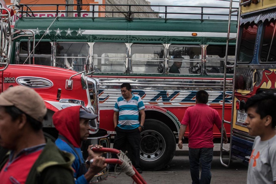Ônibus pintados com cores da bandeira dos EUA na rodoviária de Quetzaltenango, na Guatemala: cidade é um dos pontos de partida rumo ao Norte | KIRSTEN LUCE/NYT