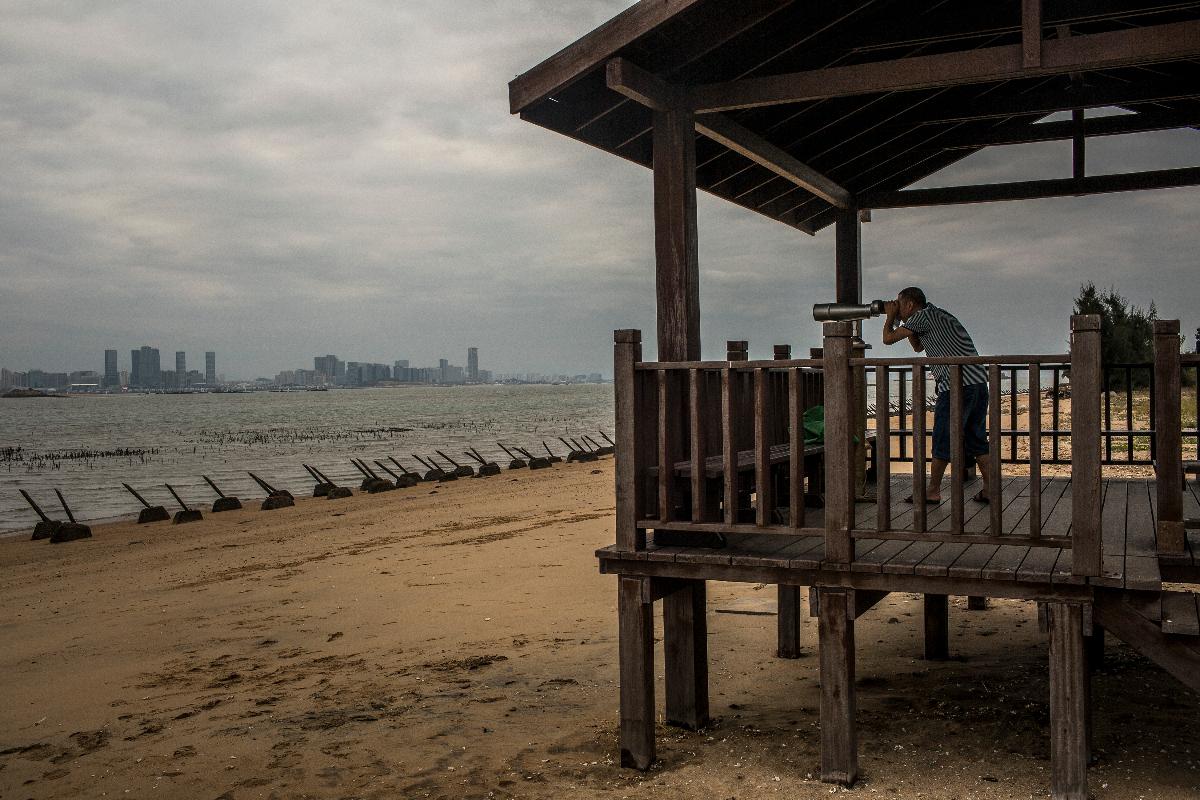 Turista chinês olha para Xiamen em uma praia de Kinmen em Taiwan | BRYAN DENTON/NYT