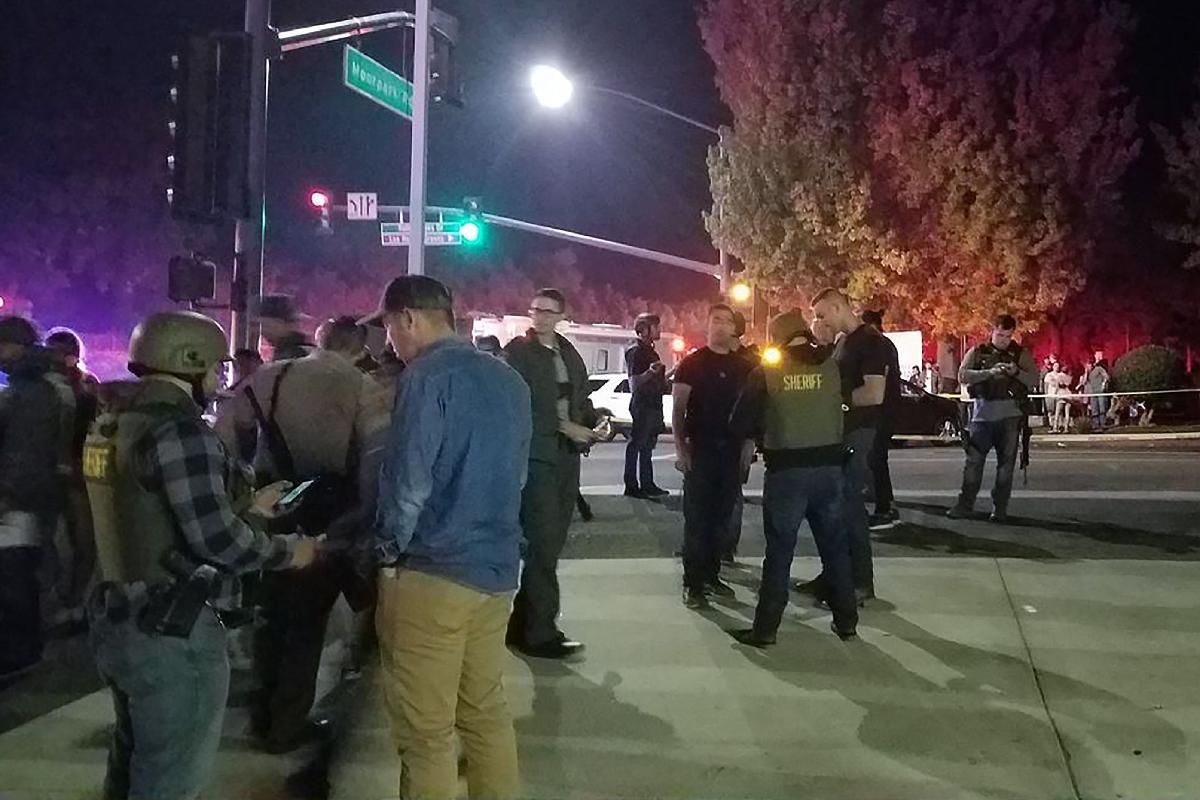 Policiais entrevistando pessoas do lado de fora de um bar de música country e salão de dança em Thousand Oaks, na área de Los Angeles, depois que um atirador invadiu o local lotado e abriu fogo | JEREMY CHILDS/AFP