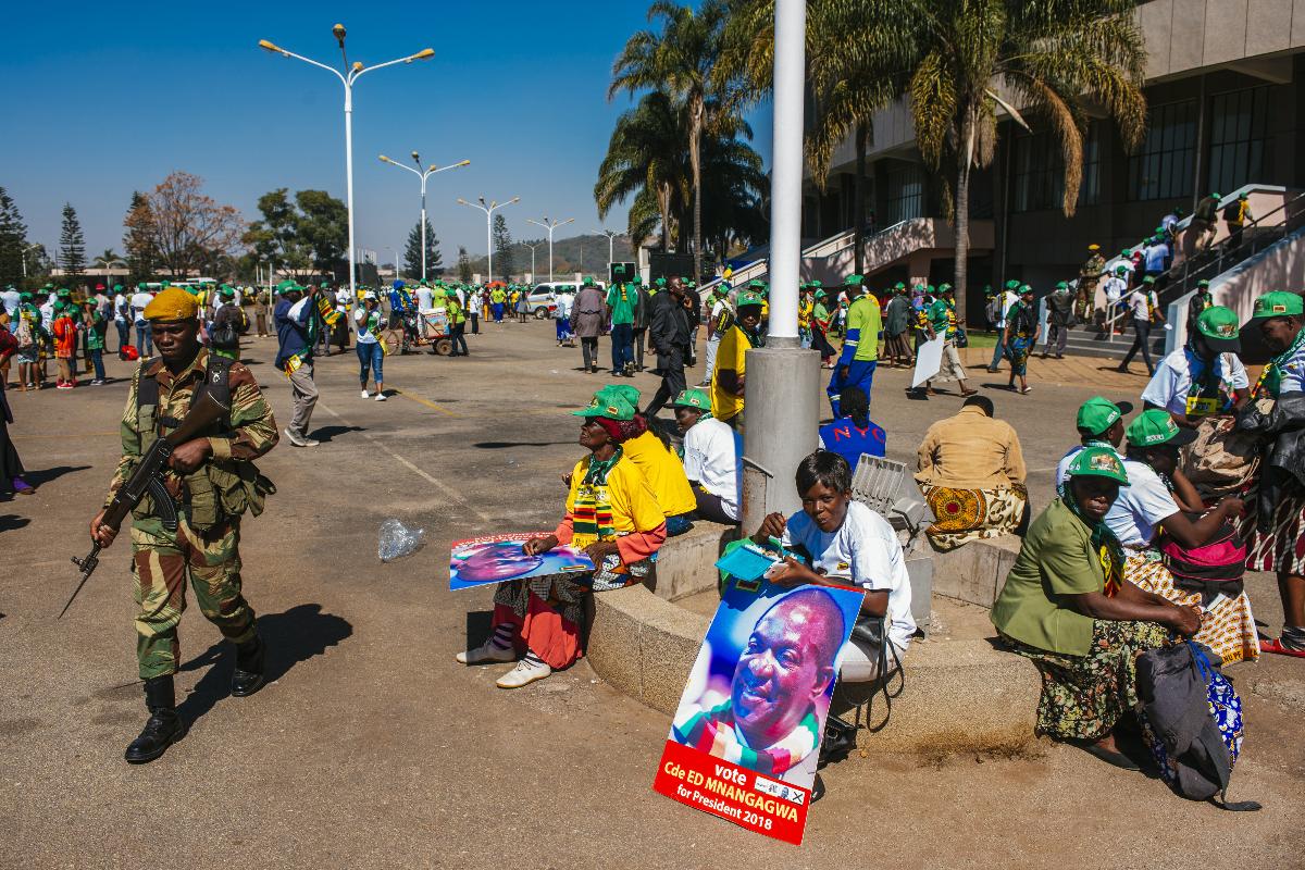 Um soldado passa por partidários de Emmerson Mnangagwa, presidente do Zimbábue, durante uma manifestação do partido no Estádio Nacional em Harare, no Zimbábue, em 28 de julho de 2018 | Waldo Swiegers/Bloomberg