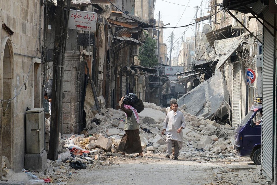 Civis caminham pelos destroços de edifícios no norte de Aleppo, Síria, em outubro de 2012, após conflito entre rebeldes e tropas do governo | phd/jh / PHILIPPE DESMAZES