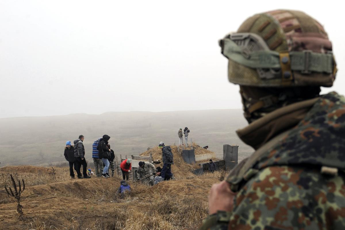 Um soldado ucraniano observa ativistas cavando trincheiras na costa do Mar de Azov, perto da cidade ucraniana de Mariupol, em 26 de novembro de 2018 | SEGA VOLSKII/AFP