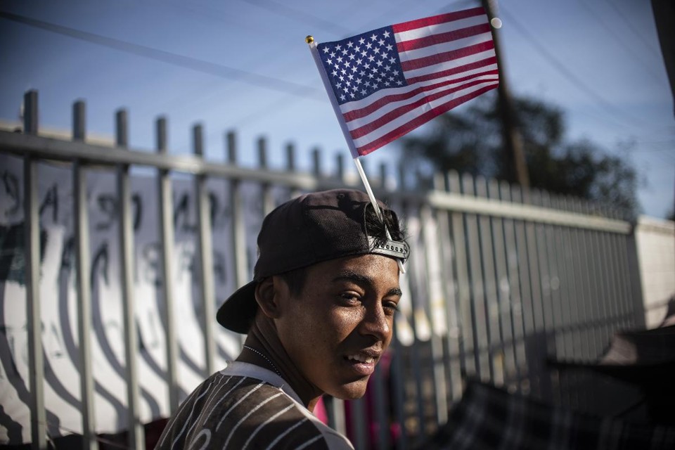 Imigrante centro-americano segura bandeira americana na fronteira entre os Estados Unidos e o México | PEDRO PARDO/AFP