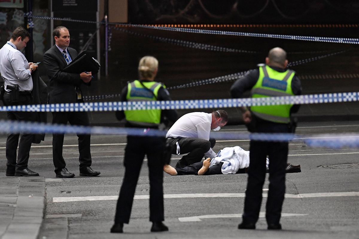 Policial inspeciona um corpo na cena do crime após atentado em Melbourne, Austrália. Uma pessoa foi morta e outras duas ficaram feridas. | WILLIAM WEST/AFP