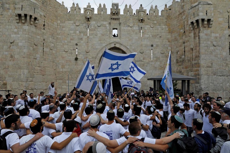 Nacionalistas israelenses agitam sua bandeira nacional enquanto celebram o dia de Jerusalém no portão de Damasco da Cidade Velha em Jerusalém, em 13 de maio de 2018. | MENAHEM KAHANA/AFP