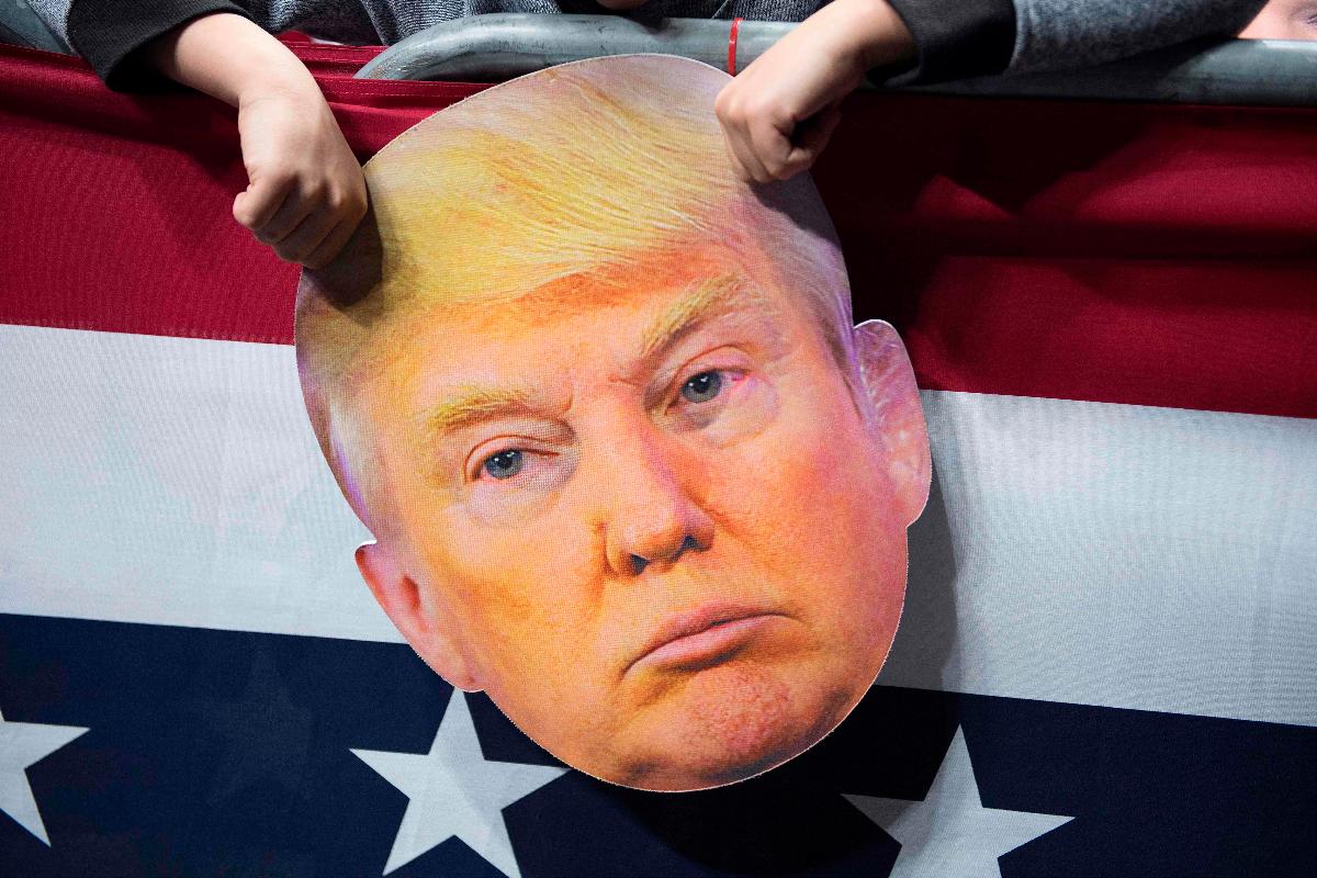 Menino segura uma máscara do presidente Donald Trump em evento de campanha em Indiana, na véspera das eleições de meio de mandato | JIM WATSON / AFP