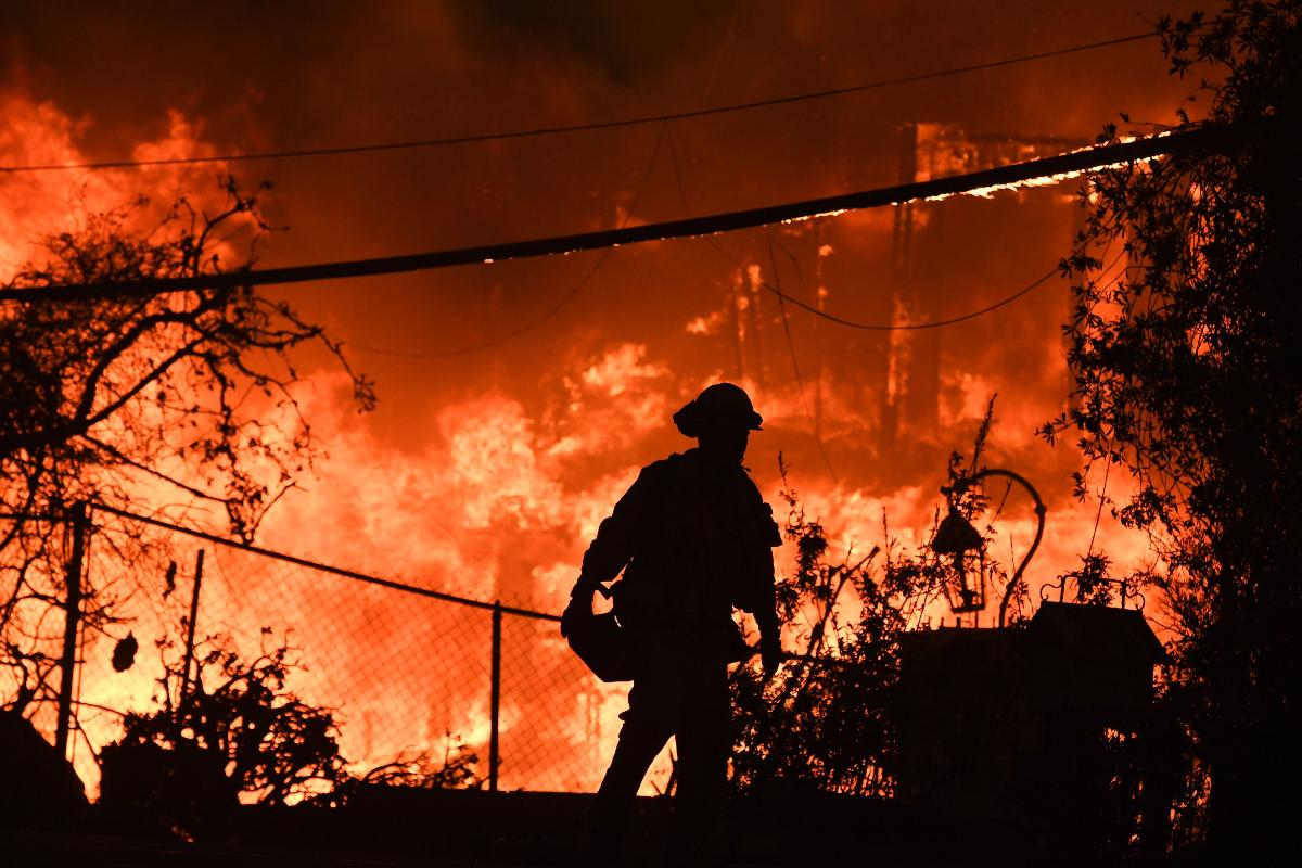 Bombieor tenta conter as chamas que atingiram uma casa em Malibu, na Califórnia | ROBYN BECK/AFP