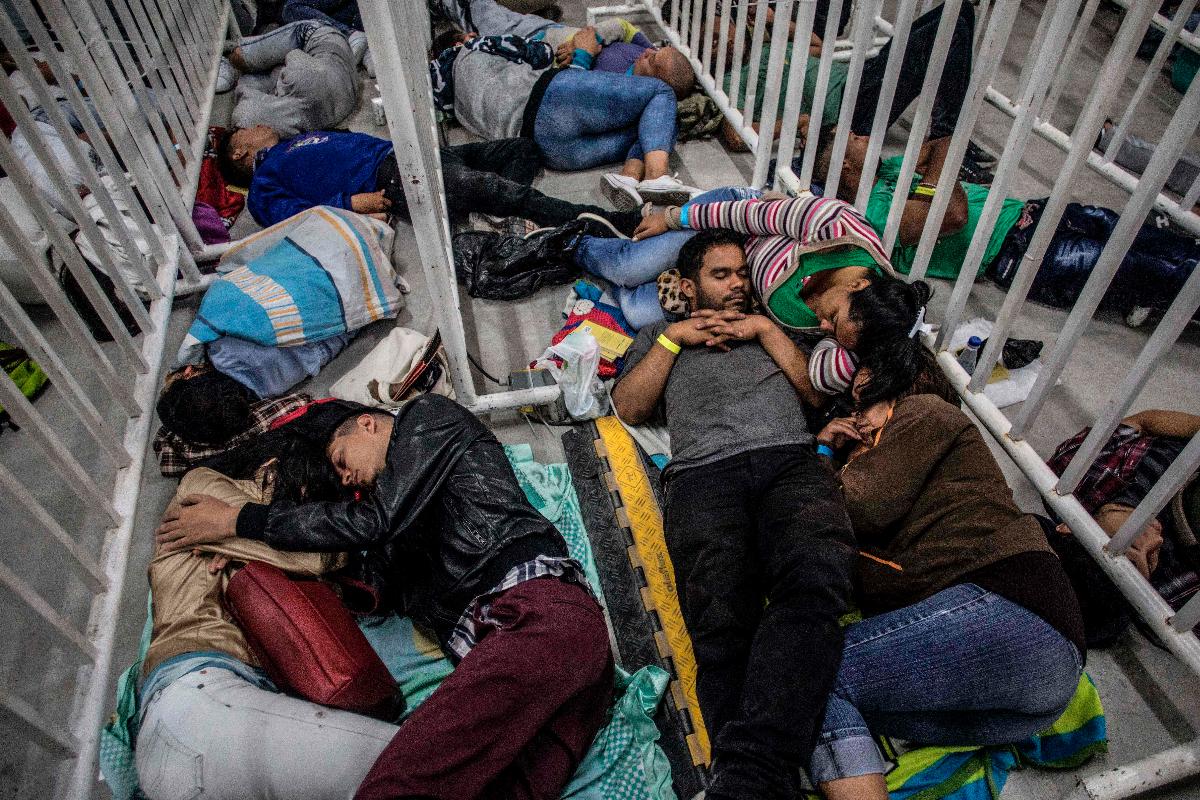 Migrantes venezuelanos que moram em Medellin, na Colômbia, dormem enquanto esperam para participar de uma Feira de Emprego | JOAQUIN SARMIENTO/AFP