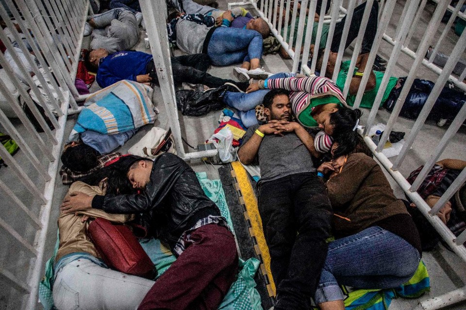 Migrantes venezuelanos que moram em Medellin, na Colômbia, dormem enquanto esperam para participar de uma Feira de Emprego | JOAQUIN SARMIENTO/AFP