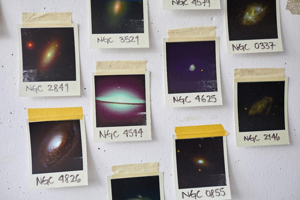 Imagens de galáxias diferentes adornam uma parede no Instituto Max Planck de Física Extraterrestre em Garching, perto de Munique. Algo muito grande e escuro ocupa o centro de nossa galáxia, e novos dados sugerem que é de fato um buraco negro | KSENIA KULESHOVA/NYT