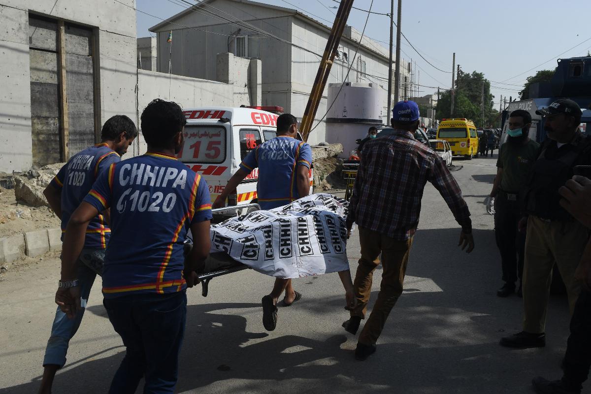 Voluntários paquistaneses transportam um cadáver em frente ao consulado chinês após um ataque em Karachi | ASIF HASSAN/AFP