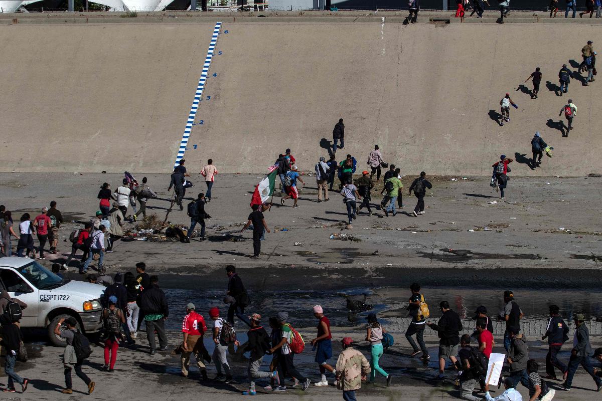 Imigrantes centro-americanos cruzam a via fluvial de concreto do Rio Tijuana, na fronteira, para tentar chegar ao ponto de passagem da fronteira El Chaparral em Tijuana, Estado de Baja California, México | GUILLERMO ARIAS/AFP