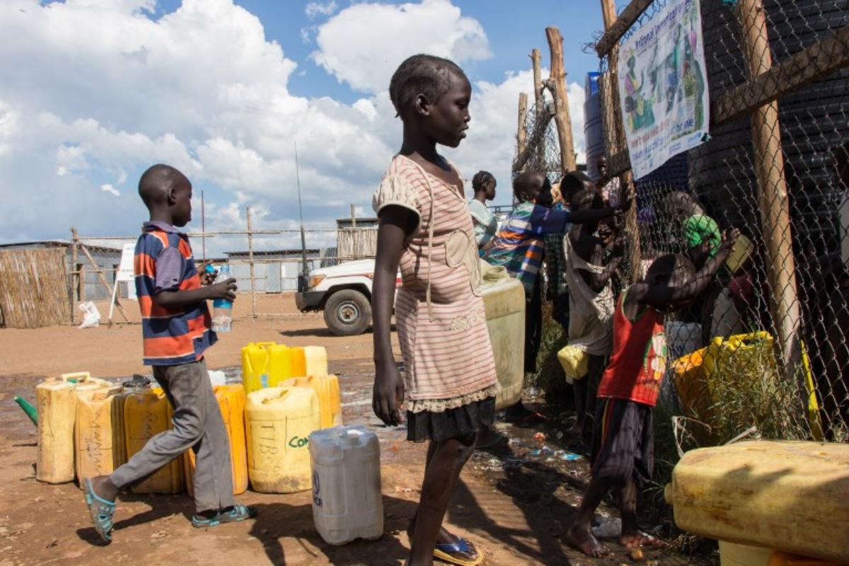 Crianças buscam água para levar para acampamento de refugiados internos em Juba, no Sudão do Sul, em novembro de 2018 | AKUOT CHOL / AFP
