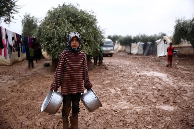 Menina síria em acampamento de desabrigados perto da vila de Shamarin, próximo à fronteira com a Turquia, em 6 de dezembro | NAZEER AL-KHATIB / AFP