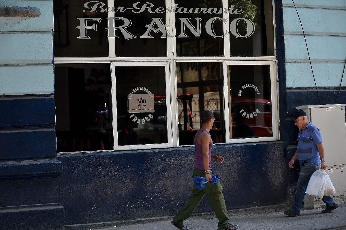 Pedestres caminham em frente ao restaurante particular Franco, em Havana, em 3 de dezembro de 2018 | YAMIL LAGE/
AFP