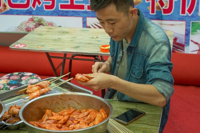 Vendedor de rua prepara asas de frango ao molho na província chinesa de Suifenhe | BigStock/