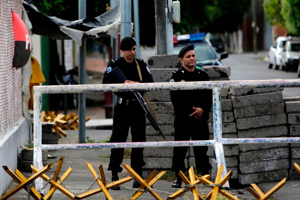 Policiais fecham o acesso aos escritórios de uma organização para direitos humanos após terem sido invadidos em Manágua, 14 de dezembro | INTI OCON / AFP