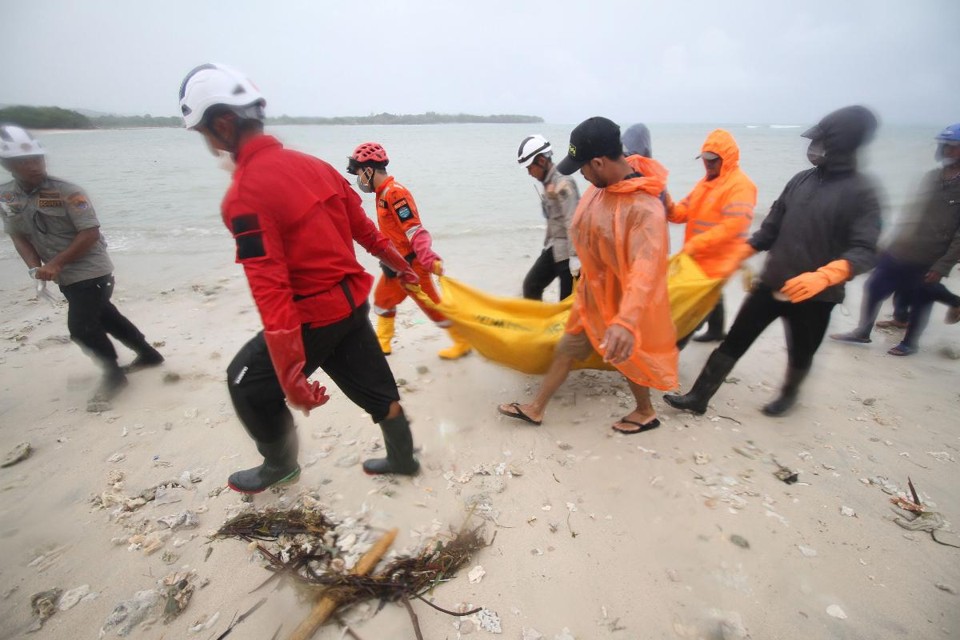 Equipes de resgate recuperam um corpo na praia em Tanjung Lesung, província de Banten, onde o popular grupo pop indonésio Seventeen fezia um show quando um tsunami atingiu a costa da ilha de Java, na Indonésia | DEMY SANJAYA/AFP