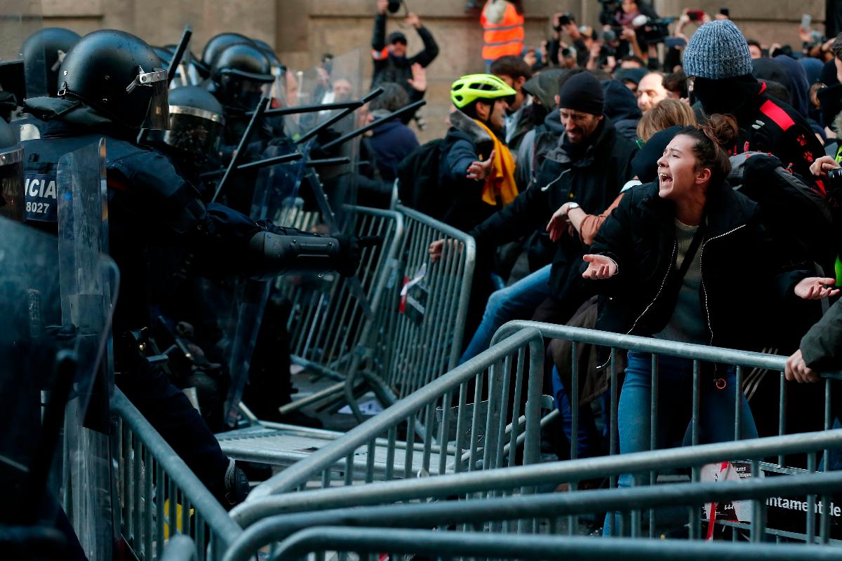 Membros da força policial regional catalã tentam manter os manifestantes atrás das barricadas de controle de multidões durante uma manifestação catalã pró-independência em Barcelona em 21 de dezembro | PAU BARRENA/AFP