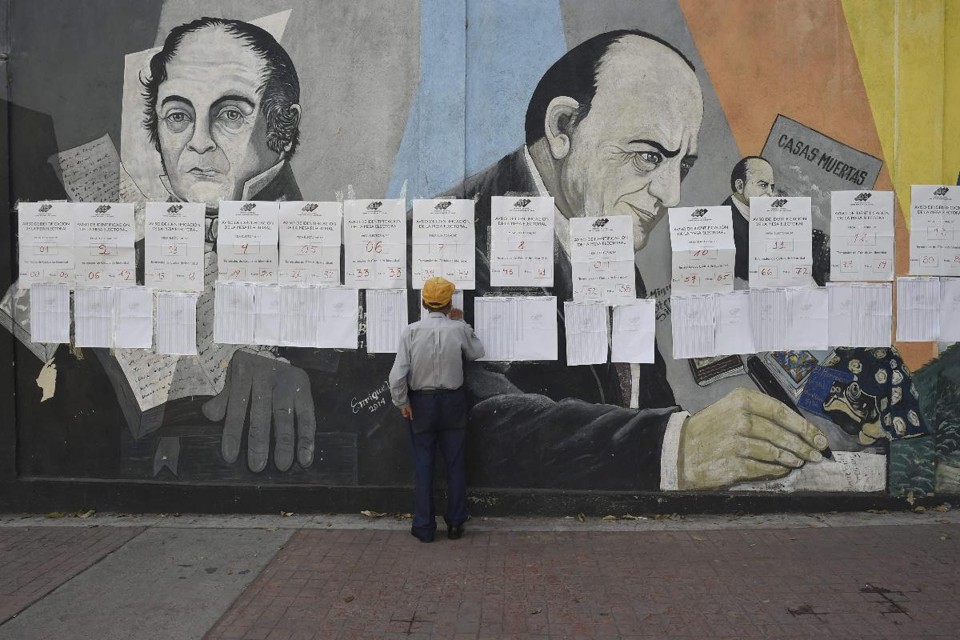 Um eleitor procura seu nome em uma seção eleitoral em Caracas durante as eleições municipais da Venezuela, em 9 de dezembro de 2018 | YURI CORTEZ/AFP