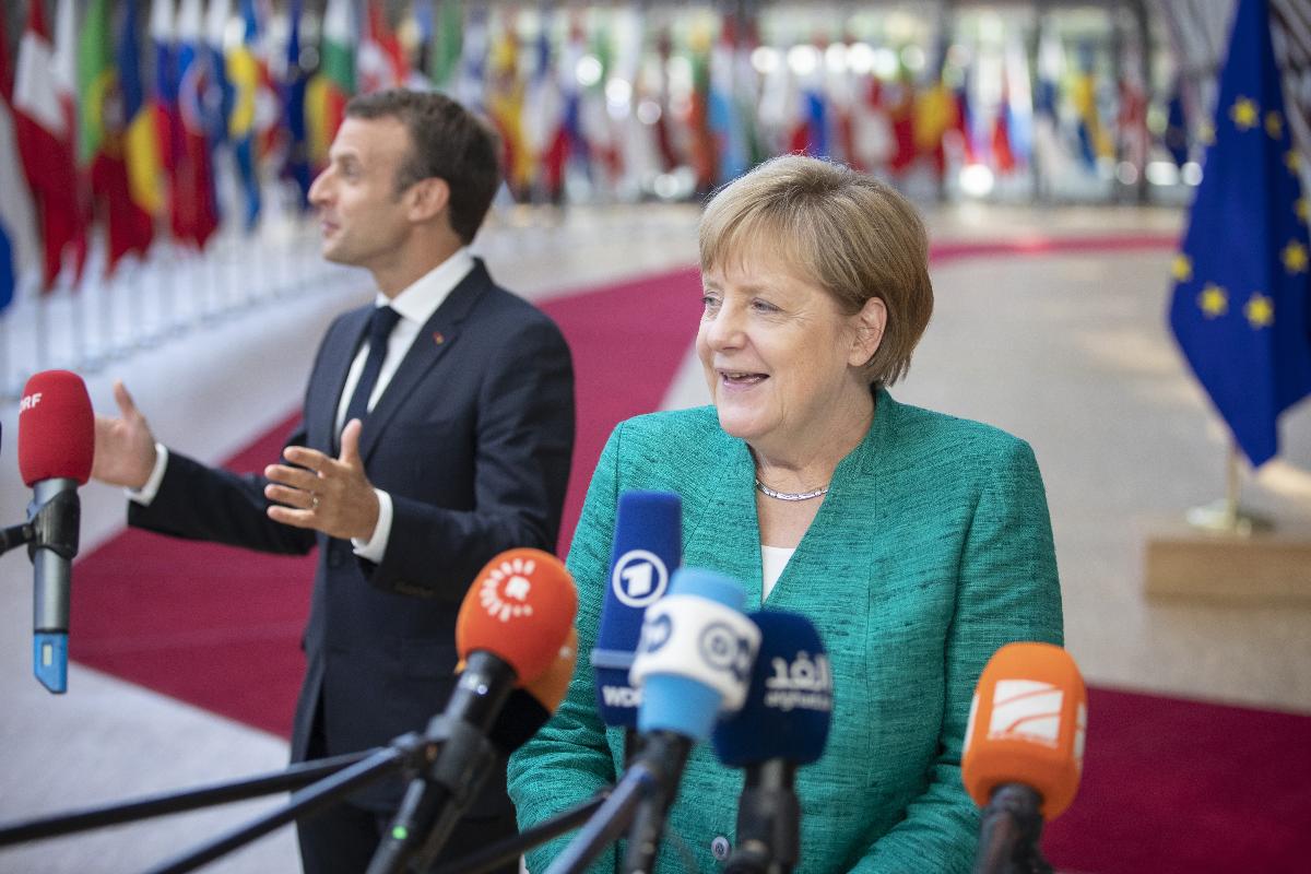 A chanceler alemã Angela Merkel e o presidente da França, Emmanuel Macron, falam com a imprensa ao chegar para uma reunião de líderes da União Europeia em Bruxelas, 28 de junho | Jasper Juinen / Bloomberg