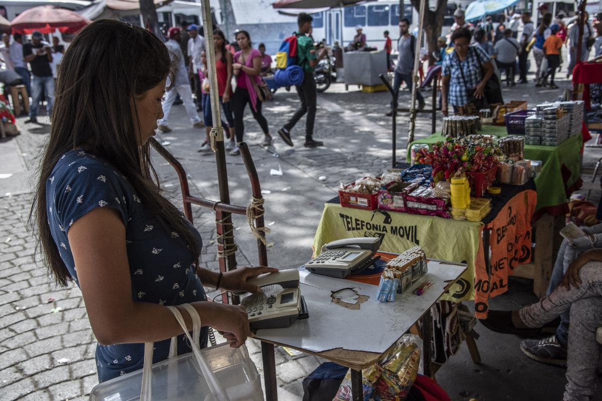 Uma mulher usa um posto de comunicação de rua, onde os telefones são alugados por minuto em Caracas, Venezuela | Carlos Becerra/Bloomberg